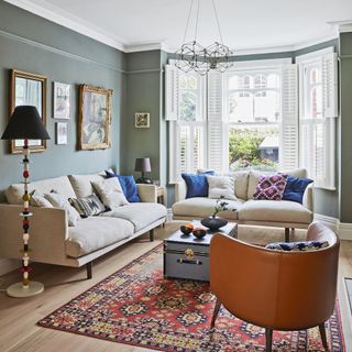 brown armchair in living room with patterned rug, coffee table and two cream sofas