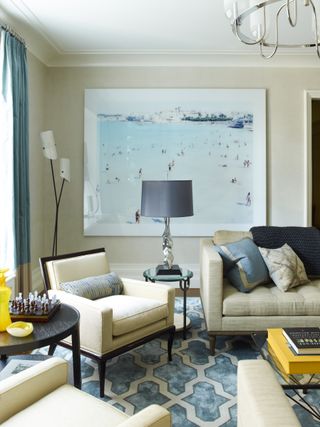 blue and white living room with blue and white rug, neutral furniture, blue lamp and blue artwork