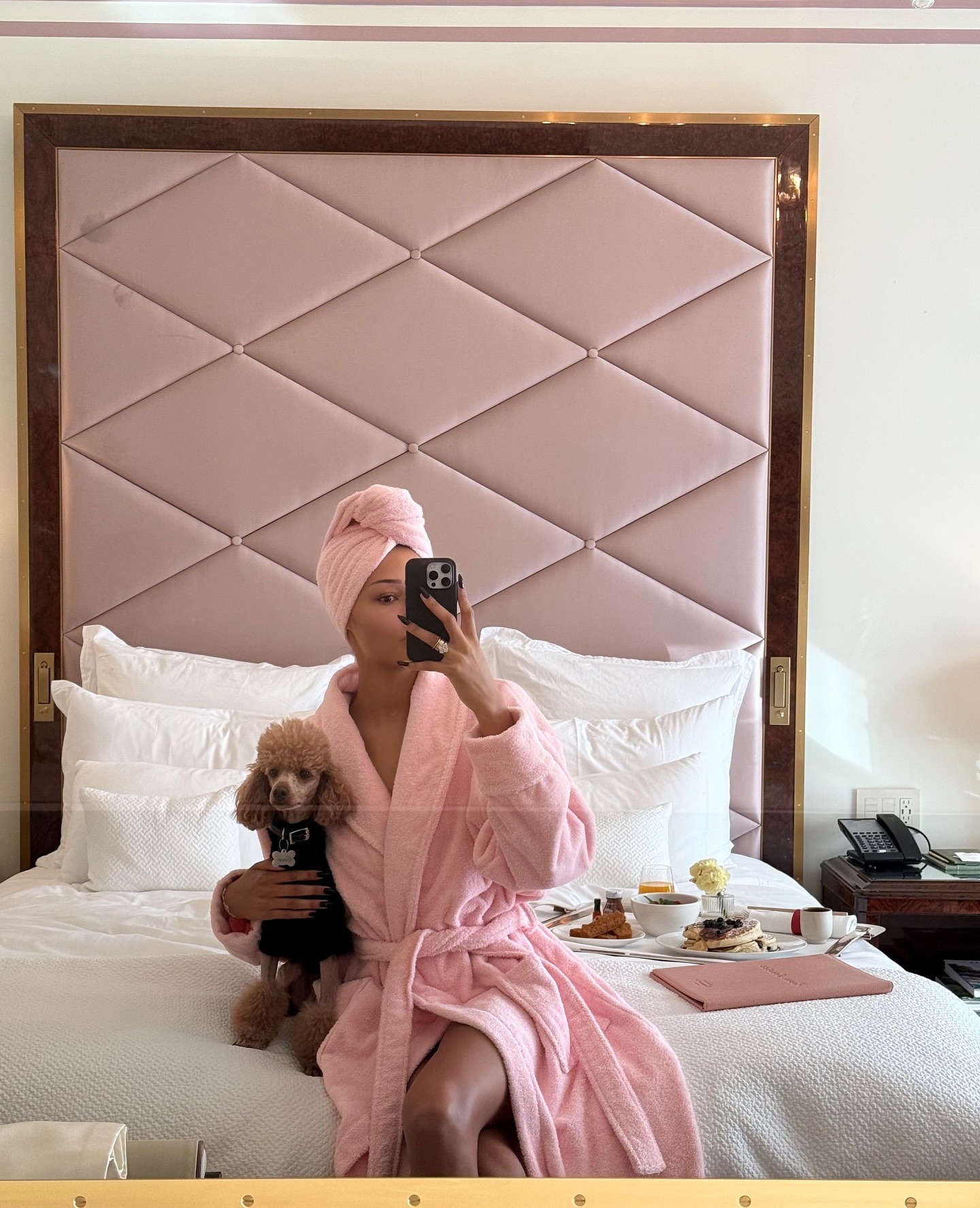 An image of Dana Emmanuelle-Jean Nozime in a robe and towel hugging her dog.