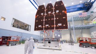 A pair of scientists stand in front of the fully completed Roman space telescope