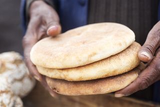 A man holds three pieces of khobz bread in Morocco