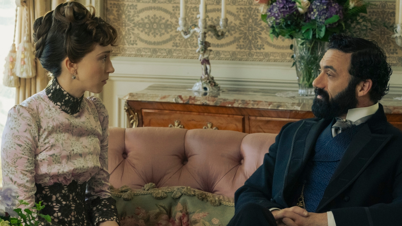Morgan Spector sits listening intently to Taissa Farmiga in the studyin The Gilded Age S3 E2, "What the Papers Say ."