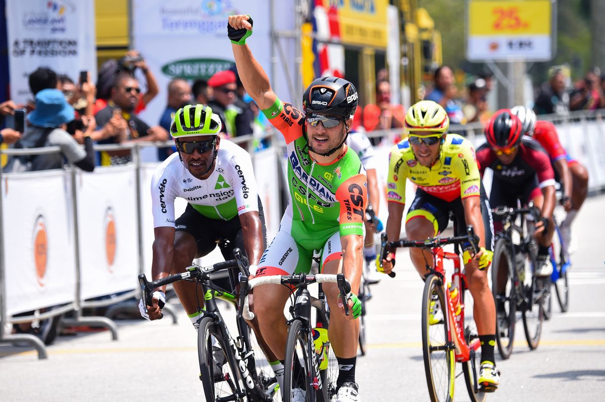 Andrea Guardini raises his arm in celebration