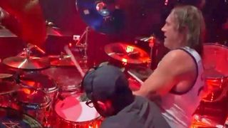 Danny Carey playing drums while his drum tech swaps in a new snare drum