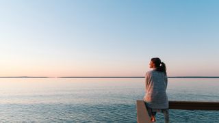 A lone woman sat on a bench looking out to sea