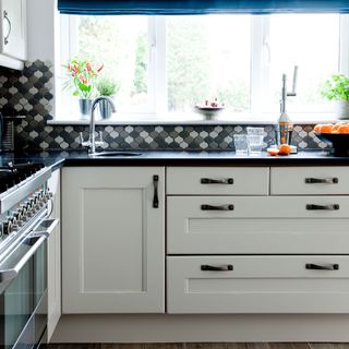 kitchen area with white cabinet and black worktop and window