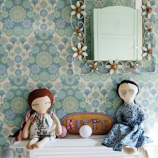 girls bedroom with patterned wallpaper and dolls