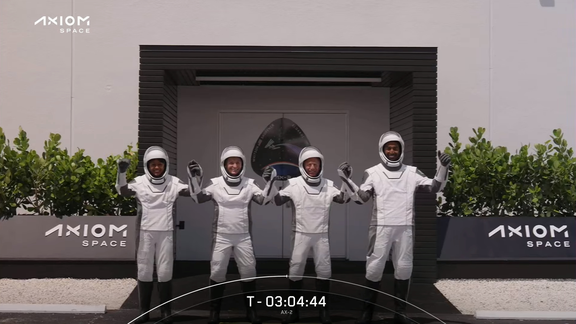 Ax-2 astronauts with their linked hands raised as they walkout in spacesuits