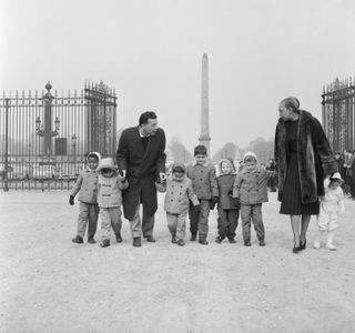 Famed entertainer Josephine Baker and her husband, Joe Buillon, stroll through the Tuileries in Paris with their seven children
