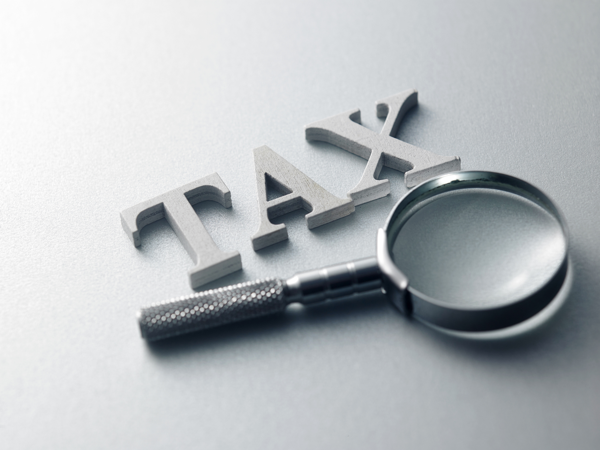 the word tax next to magnifying glass