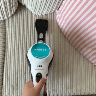 Using the furniture brush attachment of the Bosch Unlimited 7 Aqua cordless vacuum and mop to vacuum the sofa during the testing process