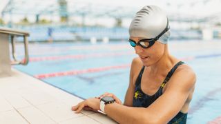 Woman checking fitness tracker at the side of the pool