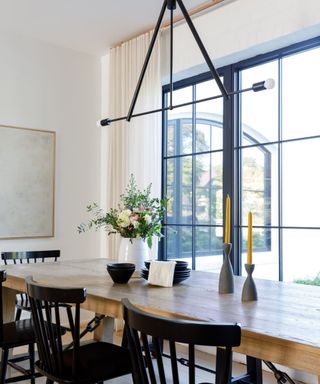 A white dining room with a wooden table and black accents