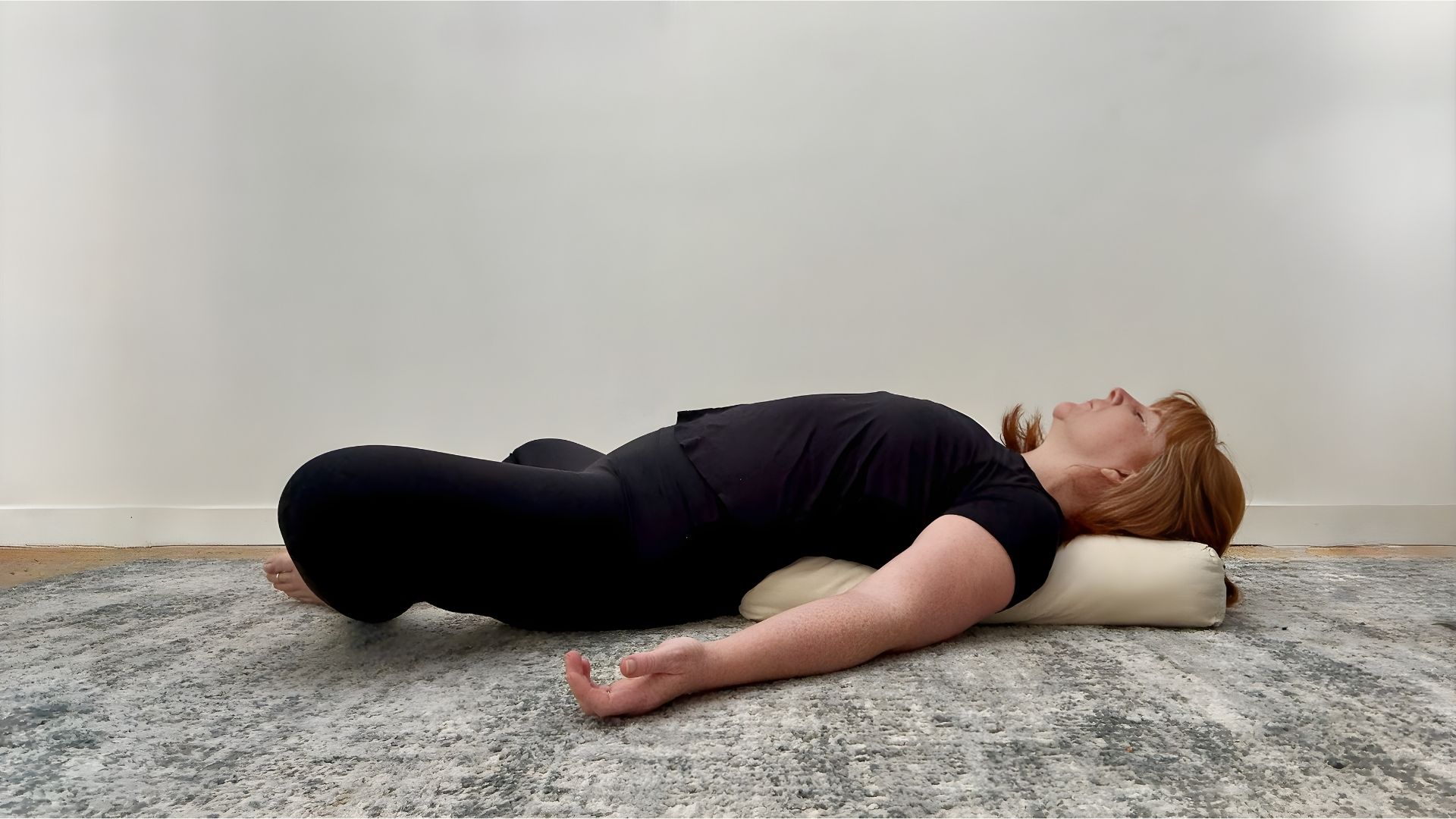 Woman in black clothing demonstrating legs up the wall yoga pose