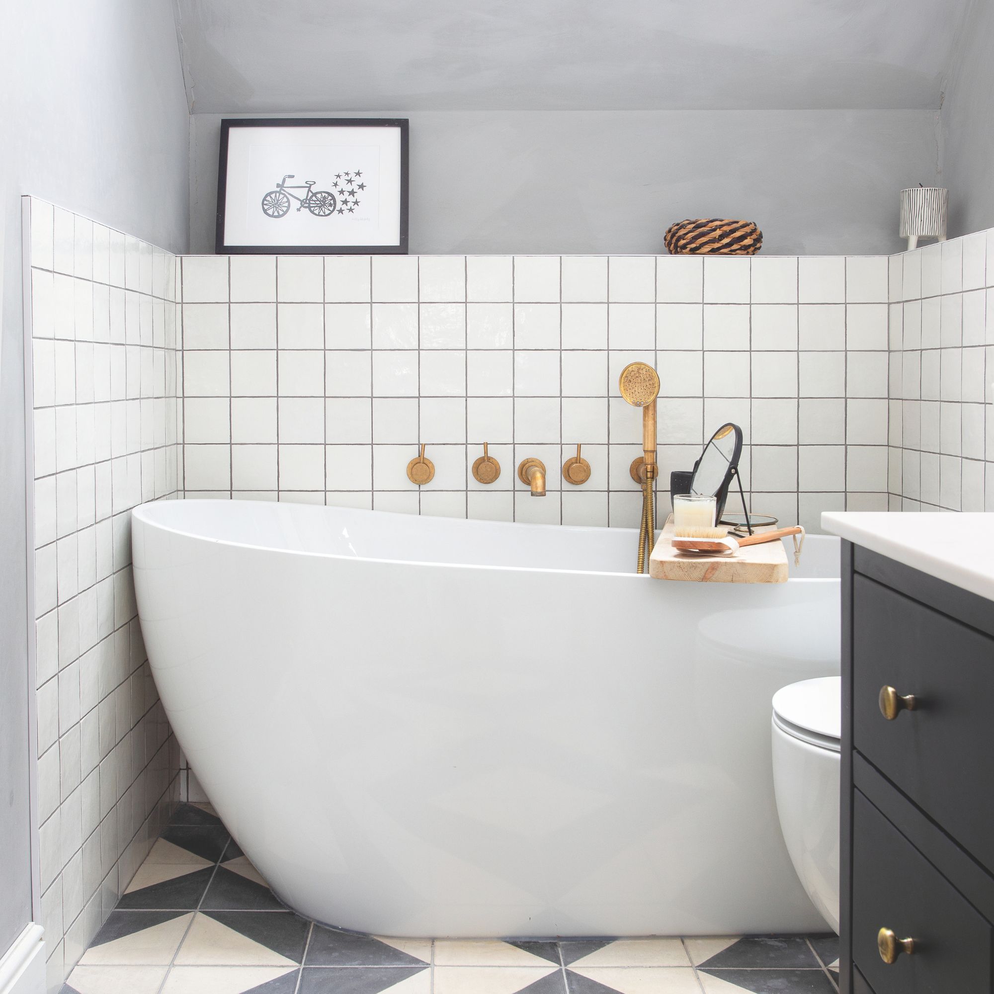 White bathtub, with brass taps, square tiles wall and patterned floor tiles