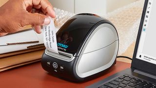 The best thermal printers; a small printer on a desk and a hand pulls a receipt from it
