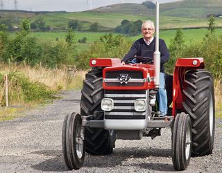 Enthusiast driving a red vintage Massey Ferguson 135 tractor during an Ayrshire Vintage Tractor and Machine Club road run