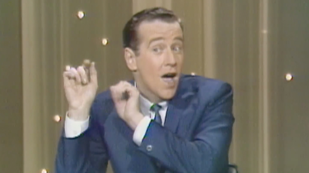 George Carlin, with short hair and a blue suit, performing standup, Archival footage used in HBO's doc George Carlin's American Dream.