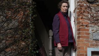 Linda Bassett as Joan in Strike - Troubled Blood wearing a fleece and standing in a doorway.