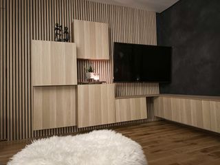 A living room with slatwall paneled media wall with wooden effect floating cabinets and a wall mounted TV