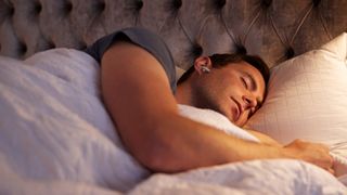 Best headphones for sleep: Man asleep in bed wearing AirPods Pro
