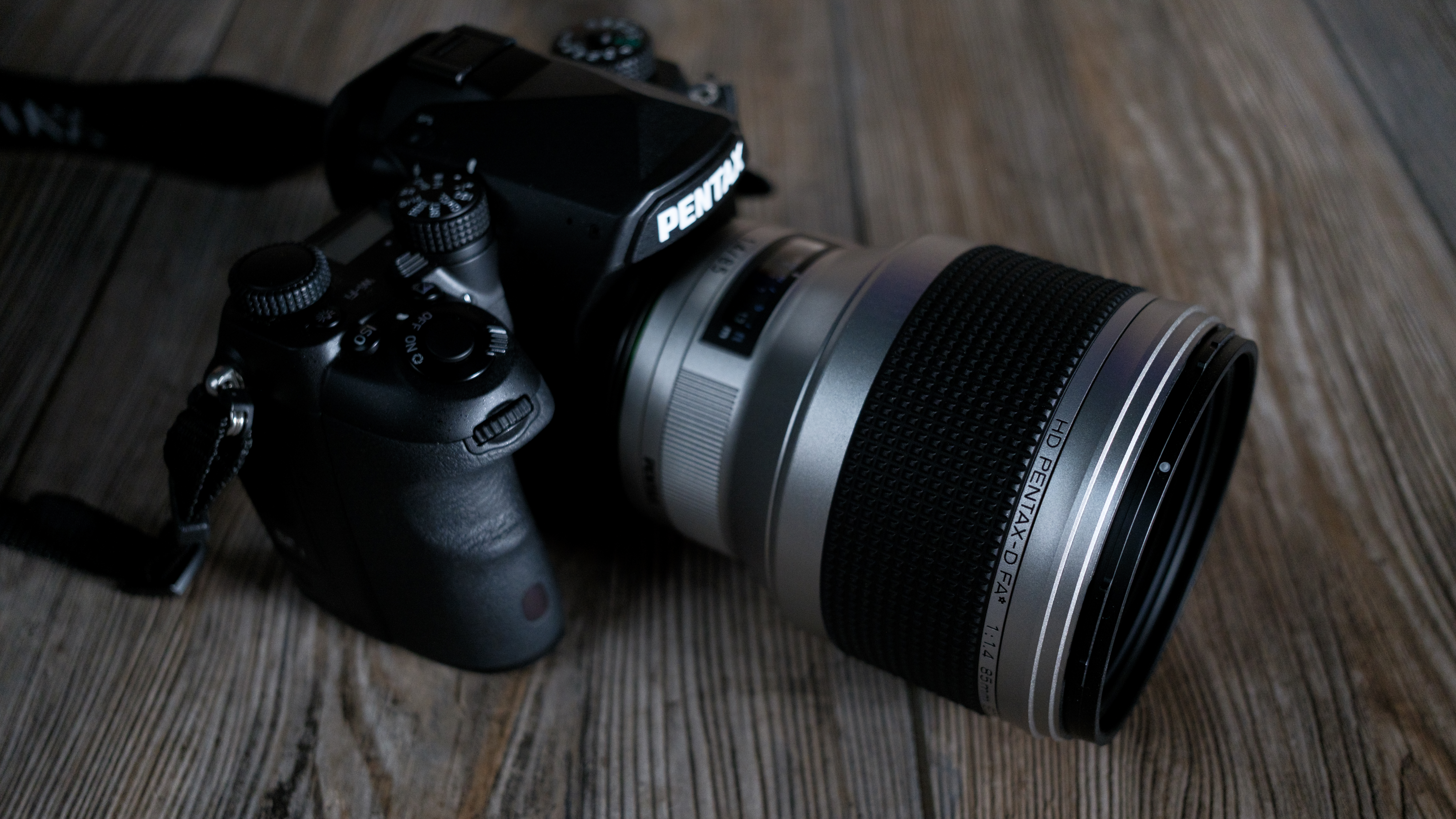 The Pentax 85mm f/1.4 SDM AW on a wood background
