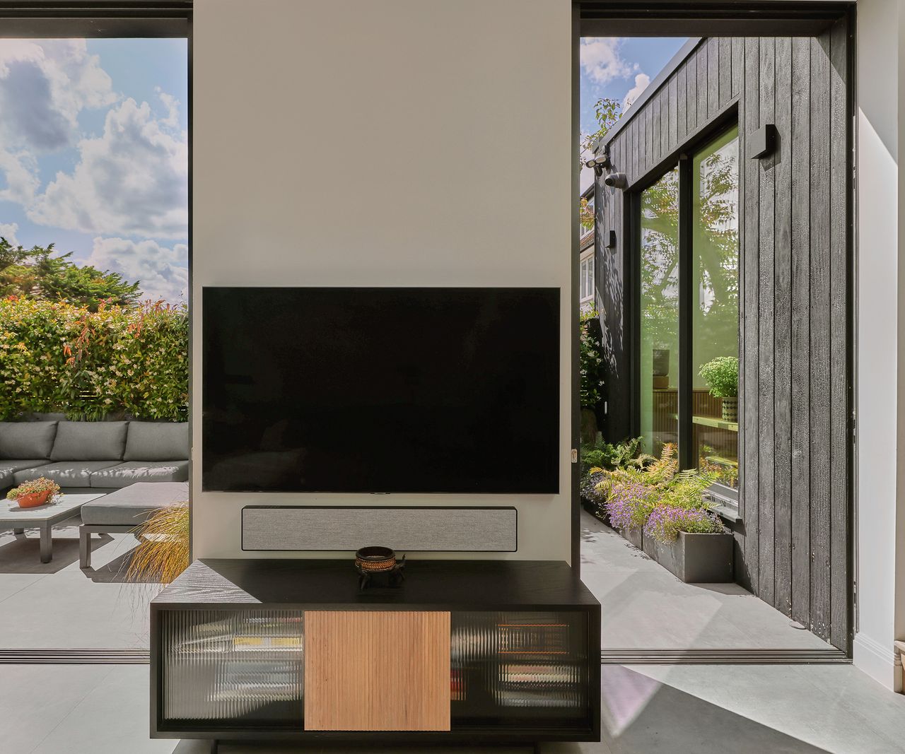 a tv mounted on a wall with open sliding doors looking out to a patio