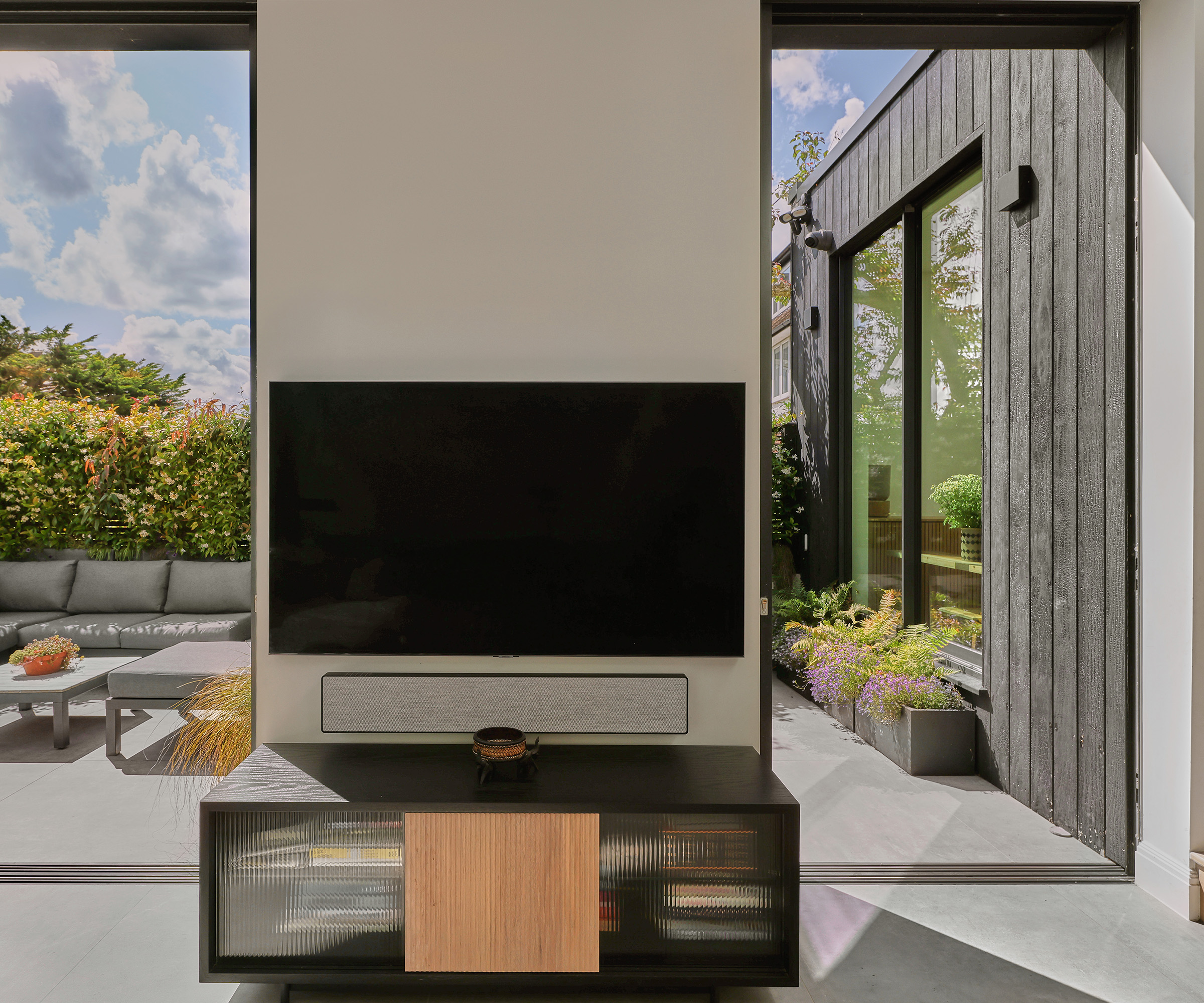 a tv mounted on a wall with open sliding doors looking out to a patio