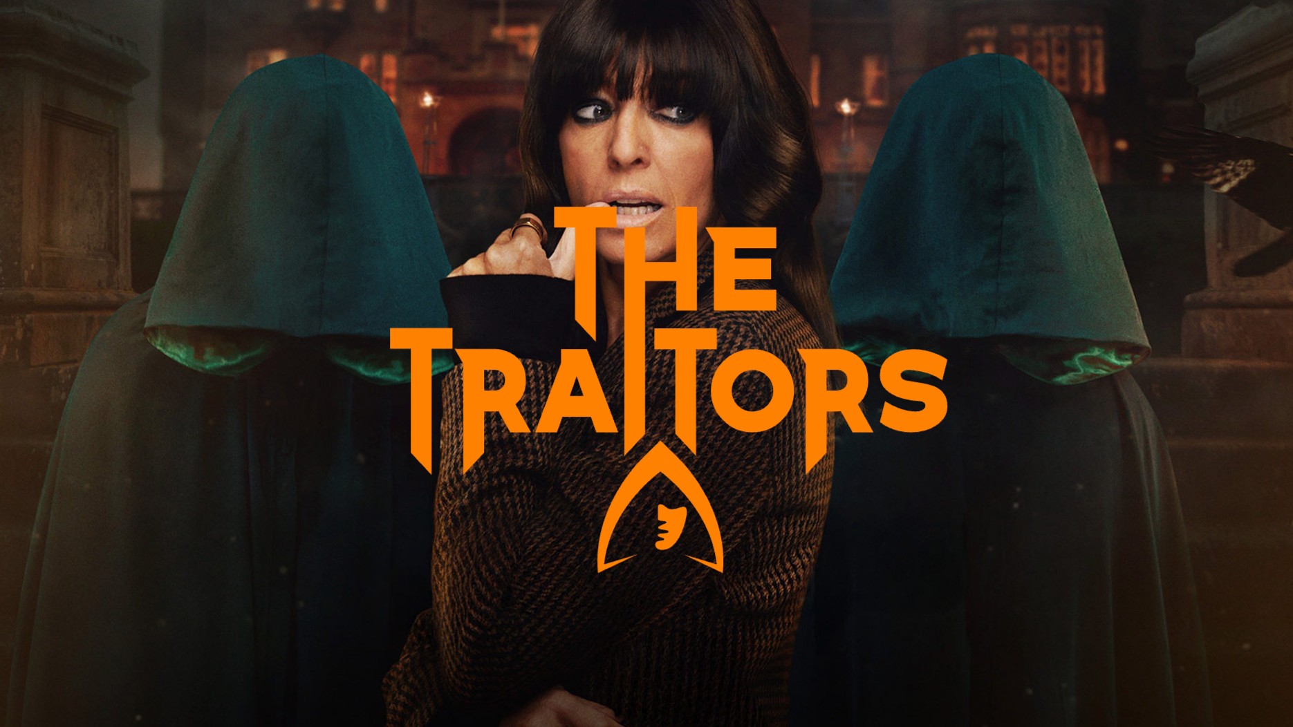Claudia Winkleman stands pensively between two hooded figures in a promotional shot for the reality series The Traitors.