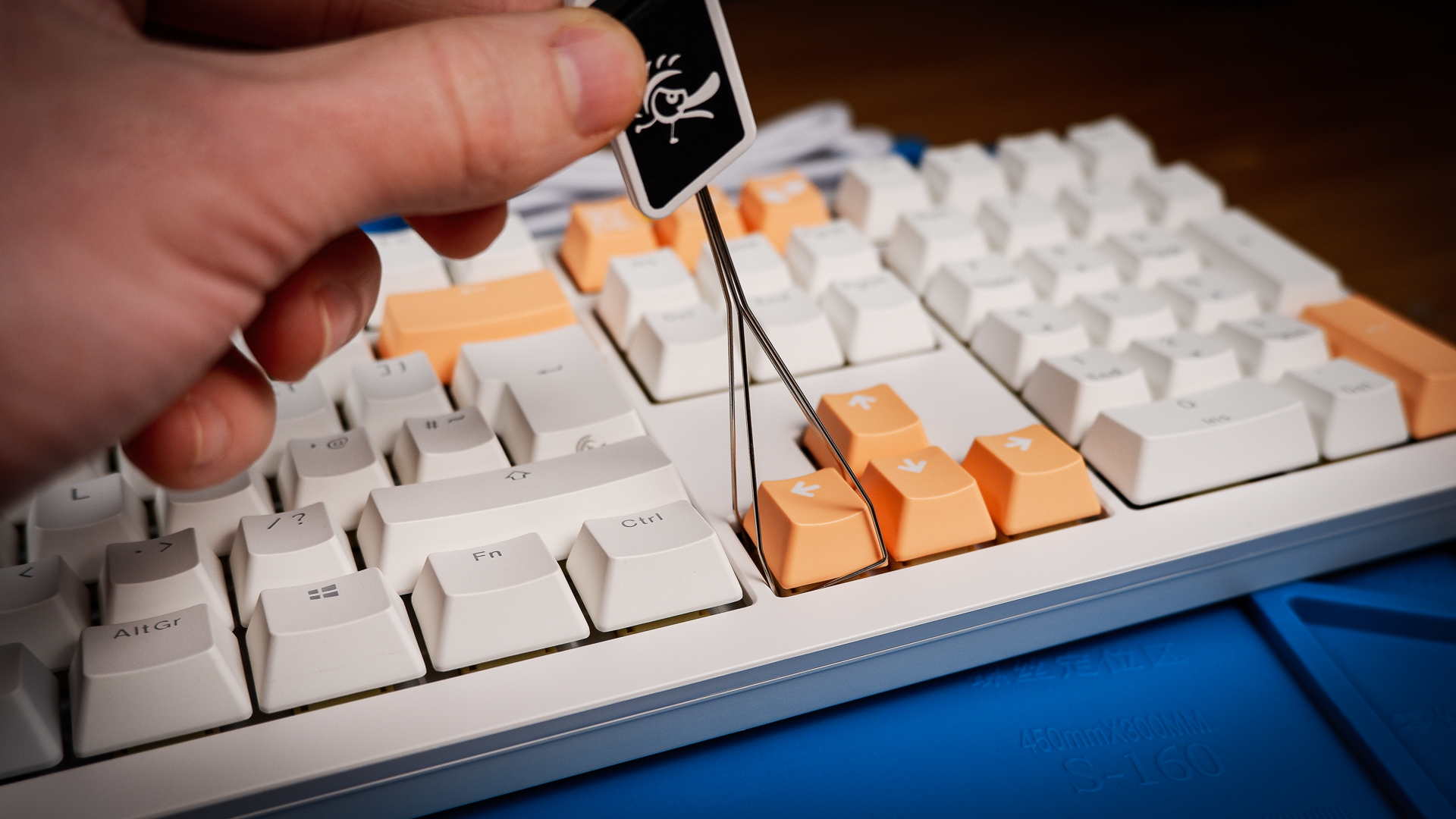 The Ducky One X induction gaming keyboard on a blue mat on a desk, with keycaps removed.