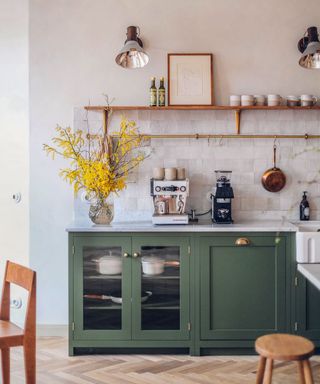 Kitchen with green cabinets, tile backsplash in neutral and shelf above