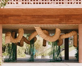 The exterior of an architectural building shows rattan and greenery sculptures hanging from the ceiling.