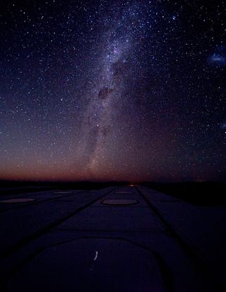 The Milky Way shines in all its majesty, as well as the Magellanic Clouds on the right. Some of the docking stations for the Auxiliary Telescopes of the VLTI lie in the foreground.
