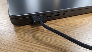MacBook Pro 16 pouces avec écran fermé posé sur un bureau en train d'être rechargé