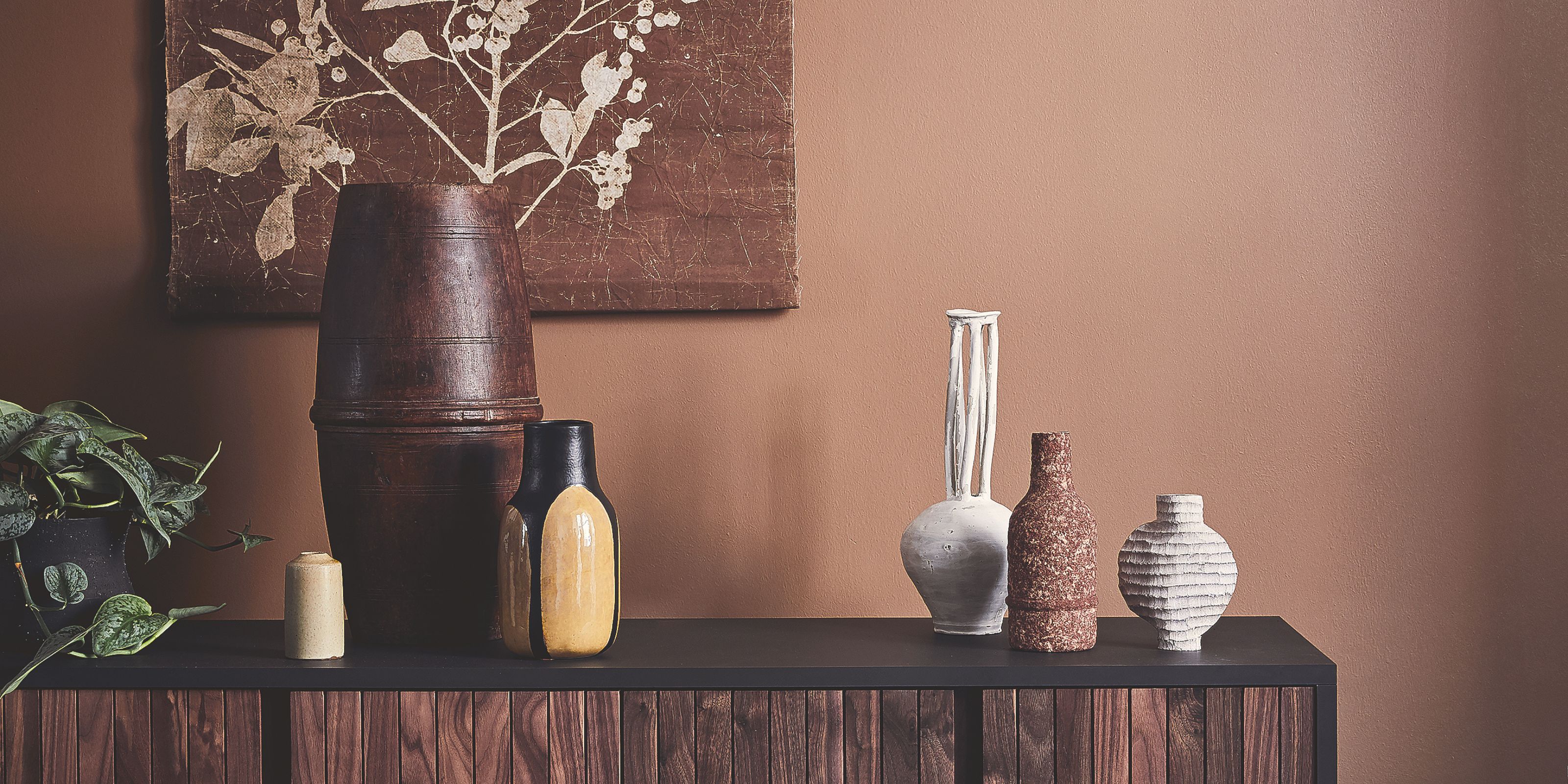 Wall painted in a neutral brown shade with dark wood and ceramic accents layered