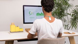 Person sat at desk wearing Upright Go 2 posture corrector