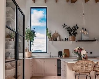 Kitchen with light pink cabinets and large window