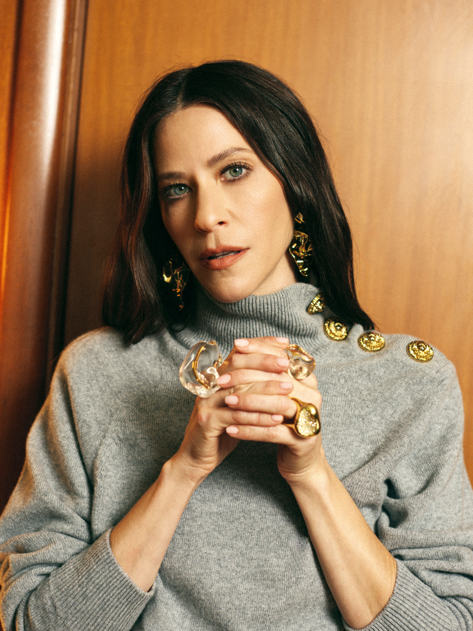 Jackie Tohn Portrait Session forBest Knockoff Luxury Clothing
. She is wearing a gray Balmain turtleneck sweater with gold button detailing on the left shoulder with matching skirt and trousers and white wedge heels and chunky Alexis Bittar jewelry.