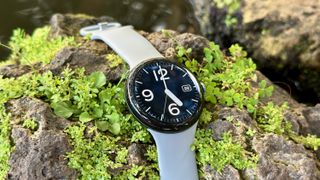 The Google Pixel Watch 3 sitting on a rock with the Pilot Bold watch face