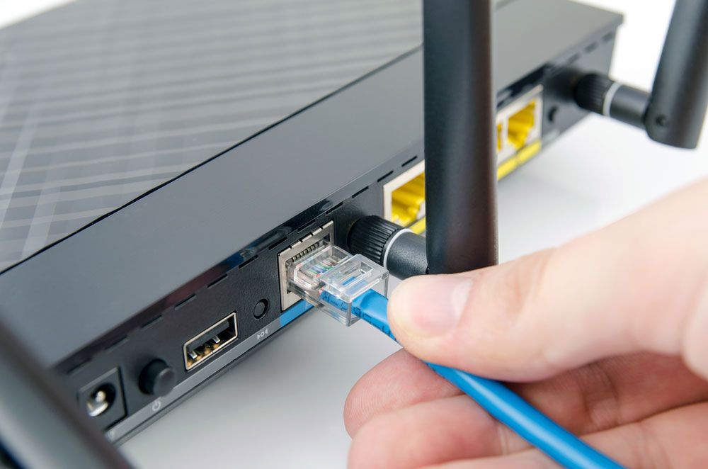 Hand plugging cable into a router Ethernet jack.