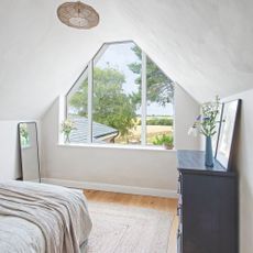 Large window in a loft conversion bedroom, looking out over countryside