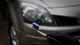 A toothbrush holding toothpaste in front of a car's headlights