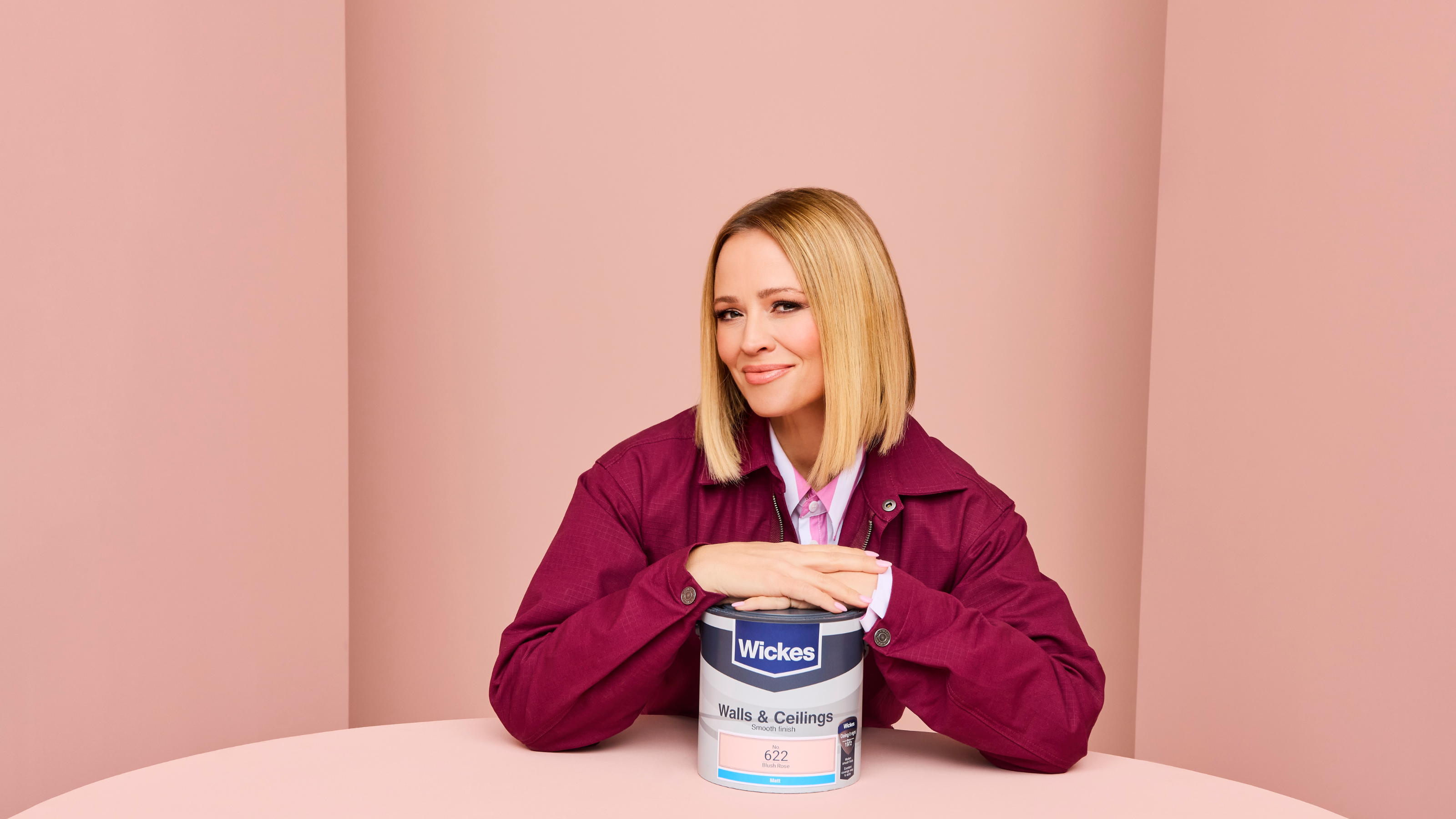 Kimberley Walsh posing with blush rose paint tin, in front of a background painted with blush rose.