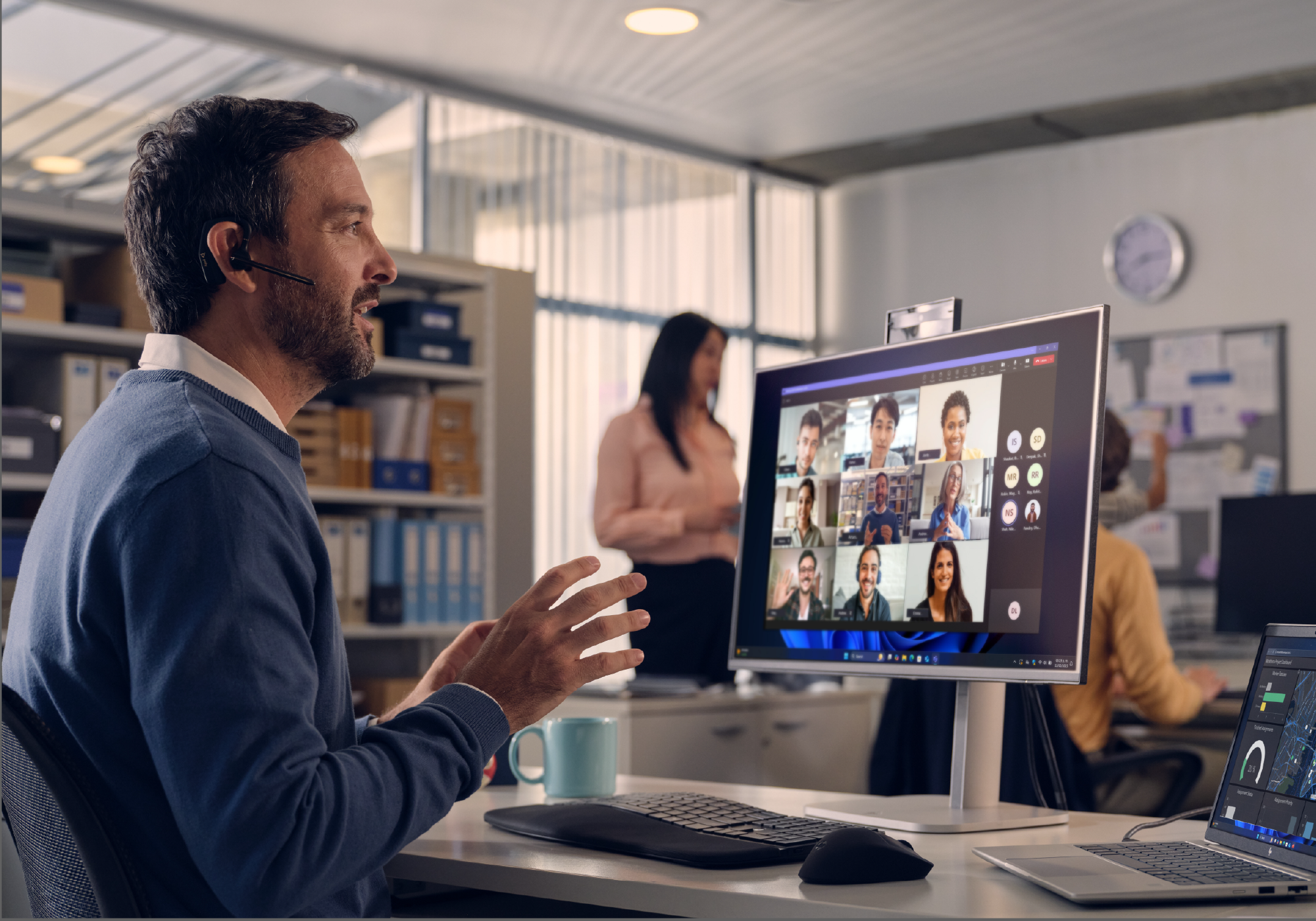 Man in office doing a video conference using his laptop and monitor