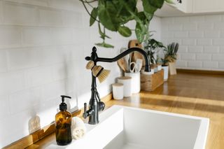 A white kitchen sink with a black faucet and an amber soap dispenser bottle.
