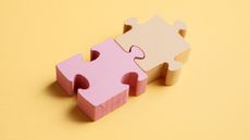 Two pastel puzzle pieces fit together against a yellow background.