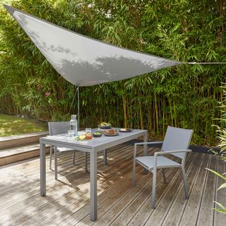 decked garden with a shade sail overhead and a table and chairs
