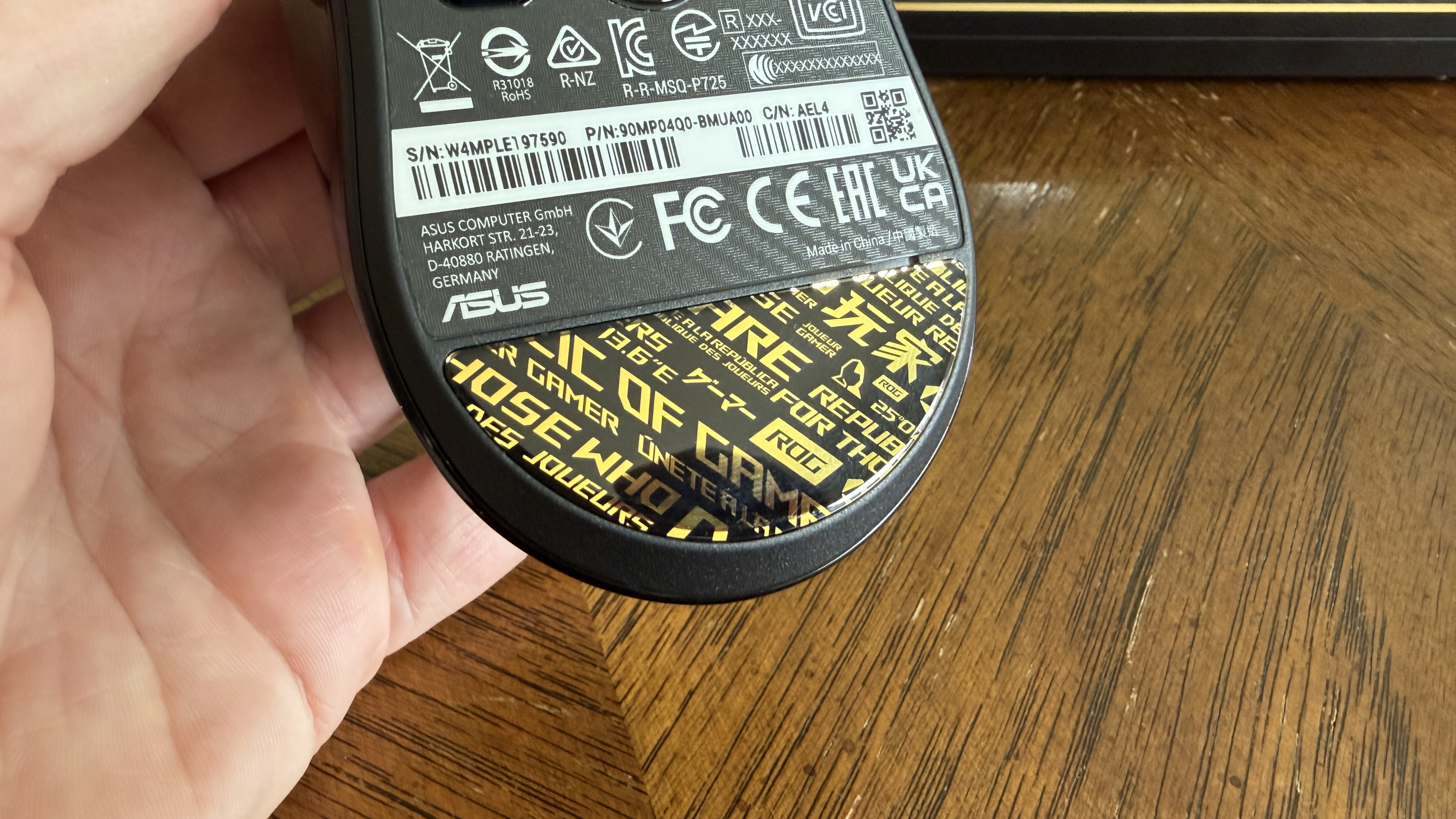 Underside of an ASUS ROG computer mouse showing labels and gaming-themed text.
