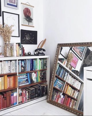 A white bookcase with a colorful assortment of books all with their spines facing forward