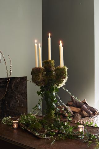 candelabra covered in moss and ivy, winter wonderland theme, on a console with tea lights